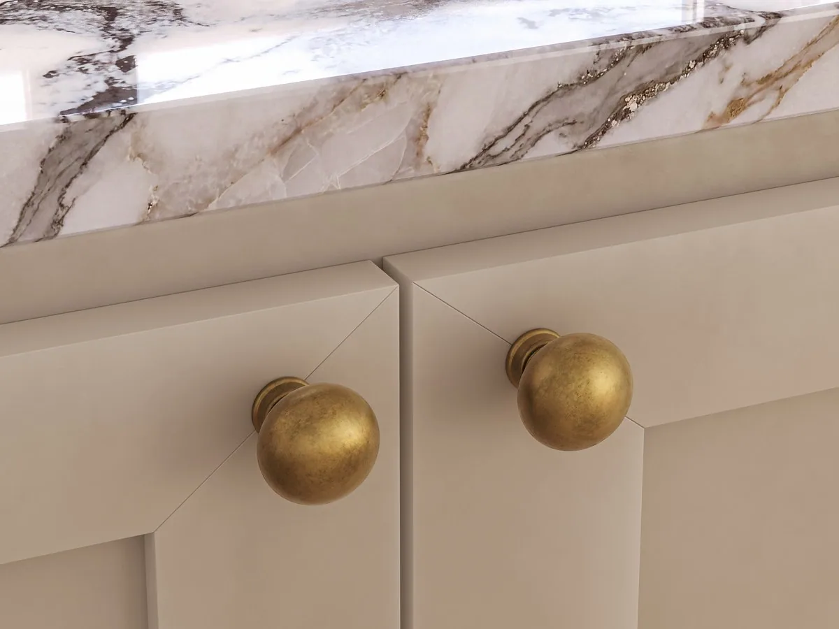 Aged brass ball knobs on cream shaker cabinetry under a marble top