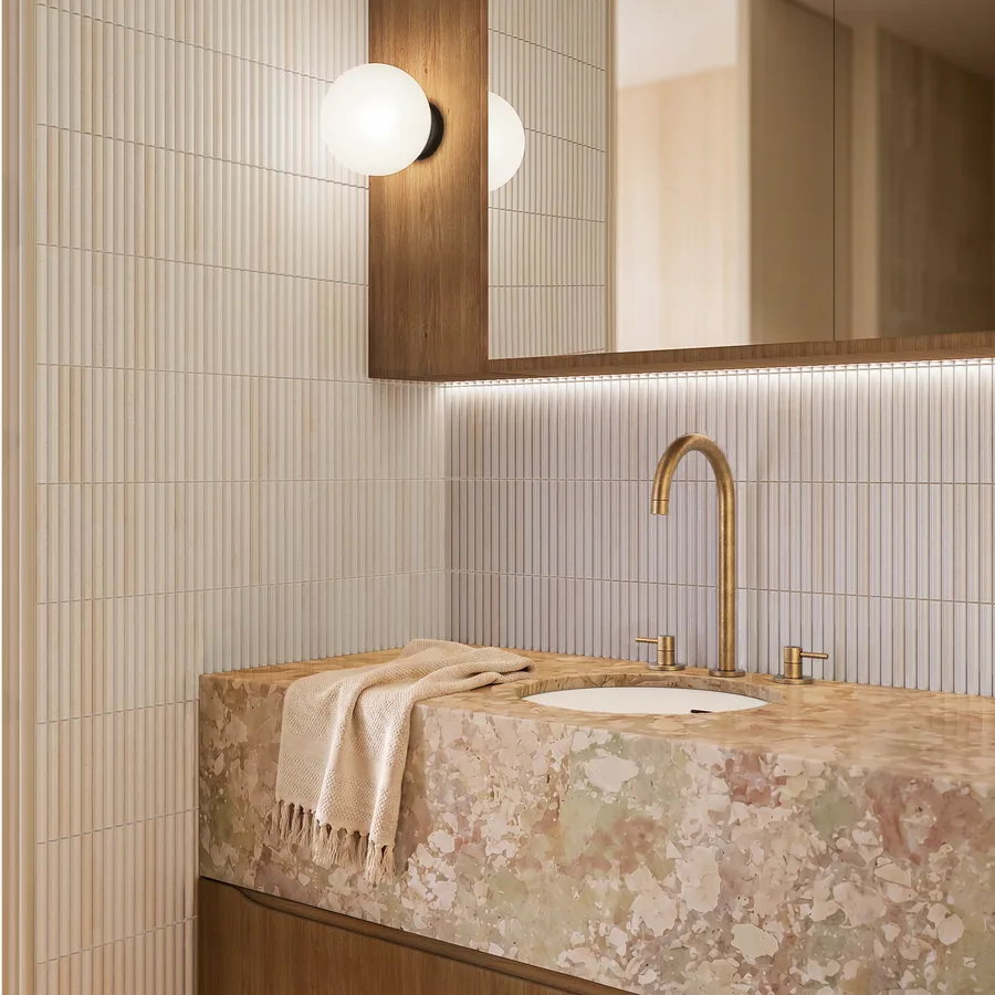 Bench-mounted taps in aged brass on rounded mosaic and terrazzo