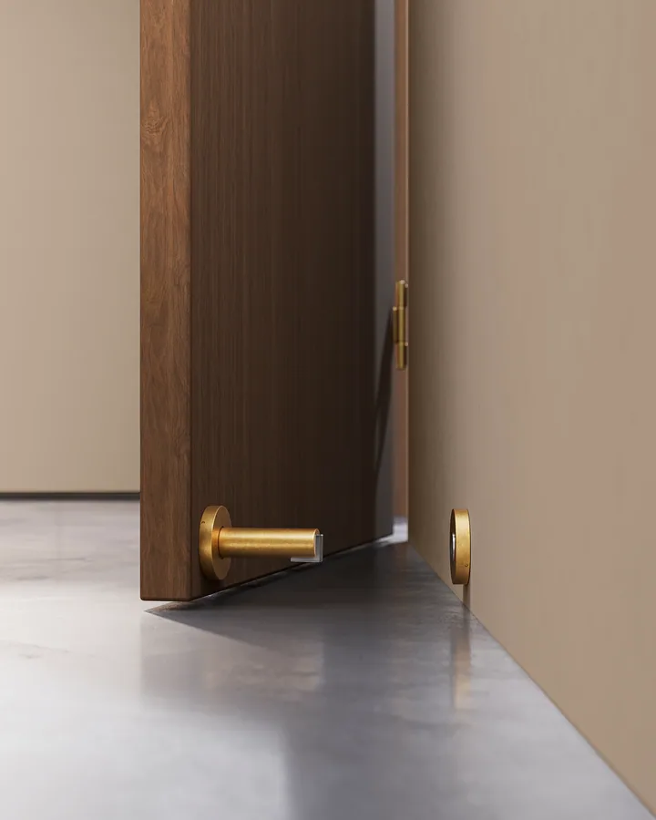 Door stop in aged brass against a walnut door